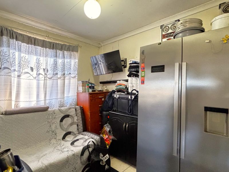 A compact living area featuring a window with curtains and a ceiling light fixture, currently utilized for storage and living space.