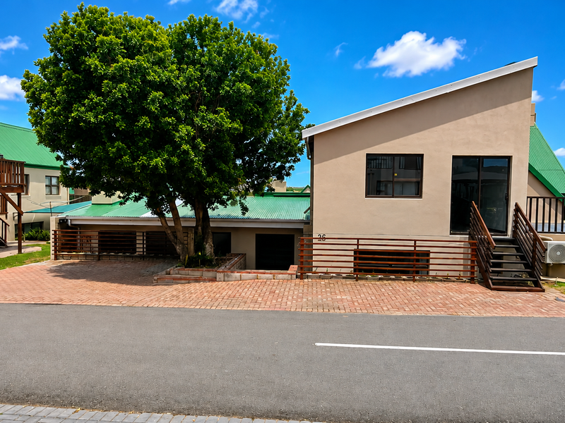 Front exterior view of a residential property featuring a paved driveway, external staircase, and modern architectural design with a metal roof.