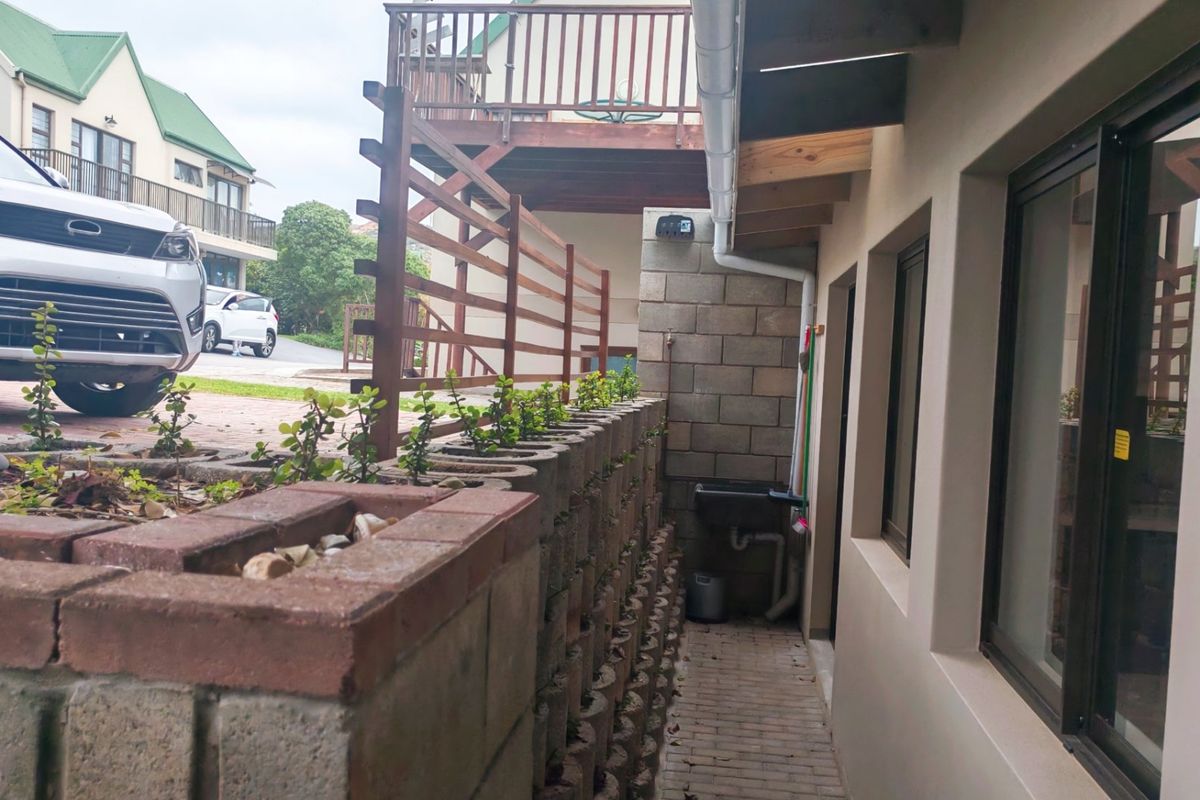 A side exterior area featuring a brick retaining wall, paved walkway, and a fixed utility sink attached to the building structure.