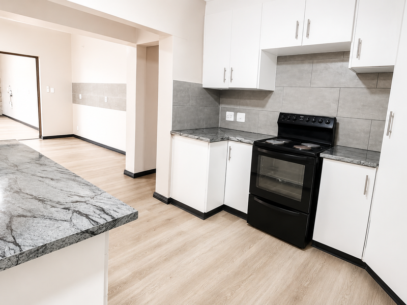 Modern kitchen featuring white cabinetry, stone-look countertops, tiled backsplash, and a freestanding electric stove, flowing into an adjacent living area.