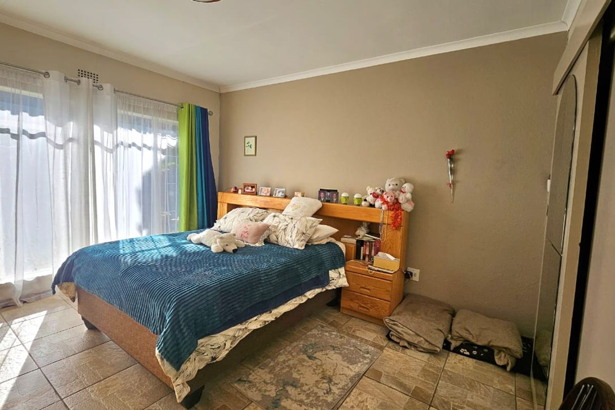 A bedroom featuring tiled flooring, a built-in wardrobe, and a sliding glass door providing natural light.