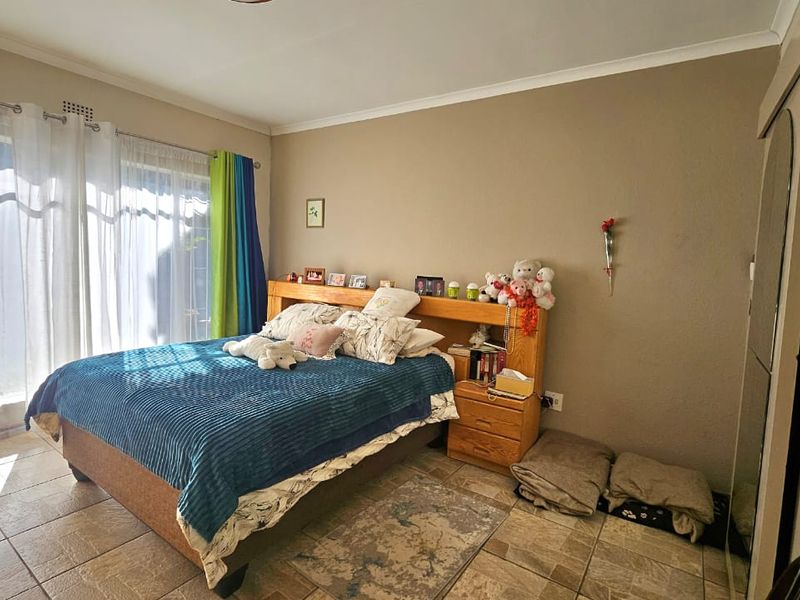 A bedroom featuring tiled flooring, a built-in wardrobe, and a sliding glass door providing natural light.