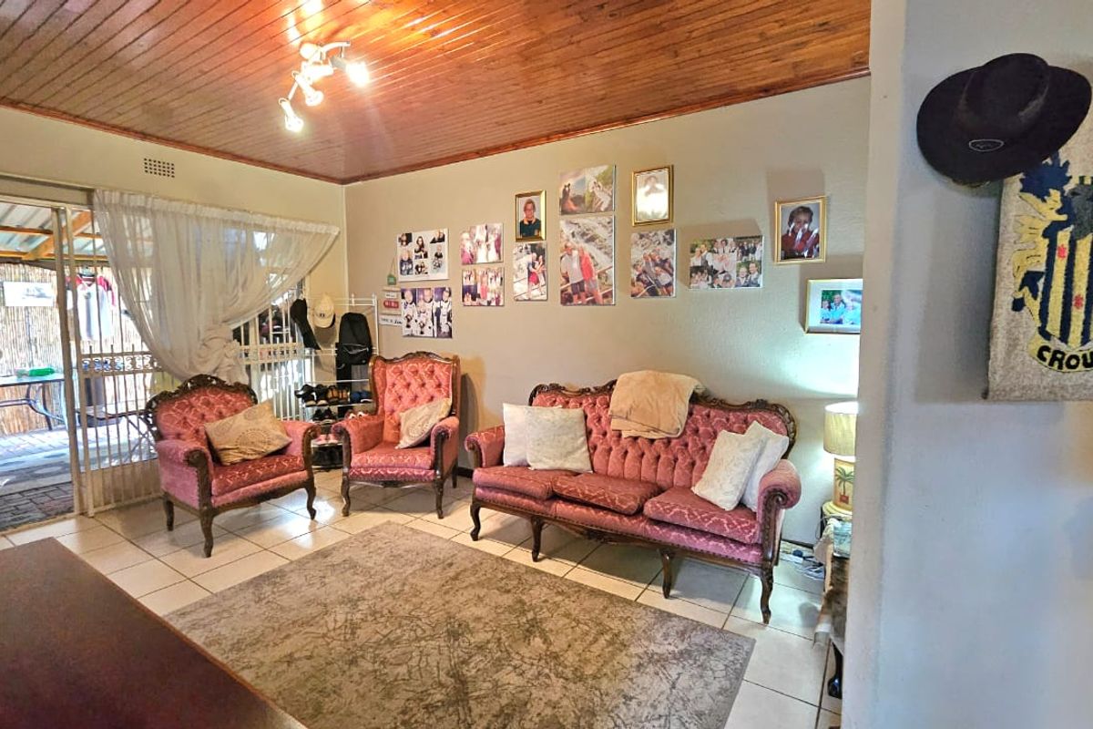 A living room featuring a timber tongue and groove ceiling, ceramic floor tiles, and direct access to an outdoor patio area through a sliding door.
