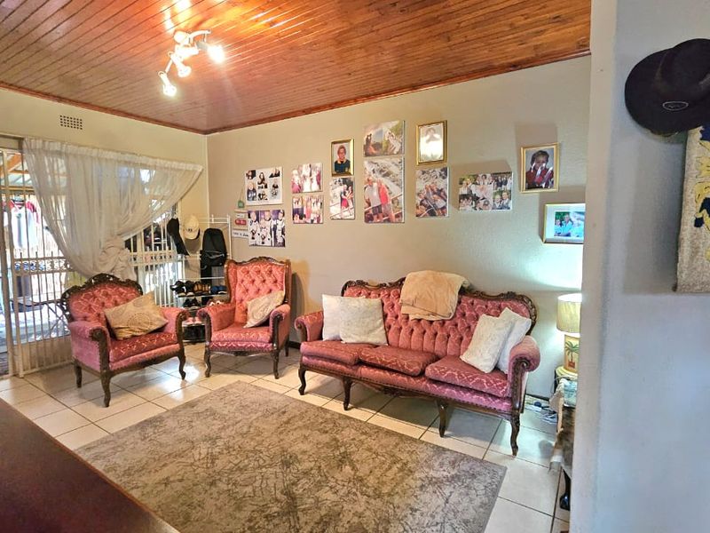 A living room featuring a timber tongue and groove ceiling, ceramic floor tiles, and direct access to an outdoor patio area through a sliding door.