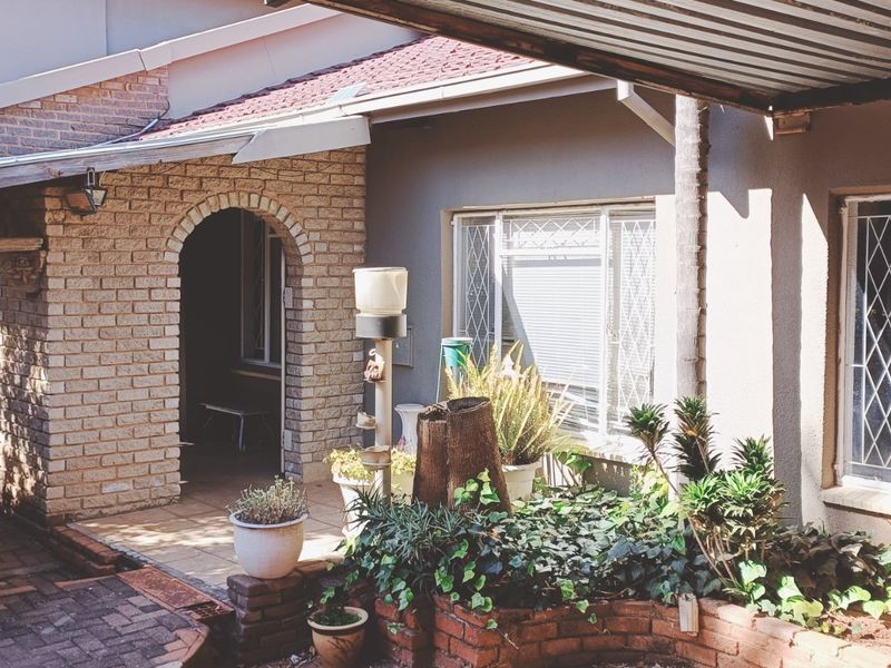 A covered patio area featuring a brick archway, tiled flooring, and built-in brick planters, providing a functional outdoor space for relaxation.