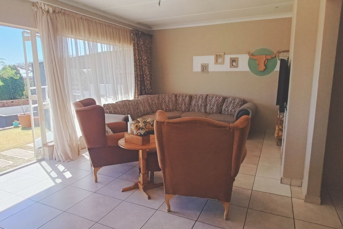 Spacious living area featuring neutral tiled flooring and large sliding glass doors that provide direct access to the outdoor garden space.
