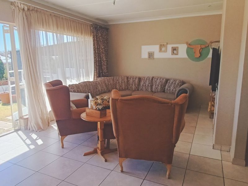 Spacious living area featuring neutral tiled flooring and large sliding glass doors that provide direct access to the outdoor garden space.