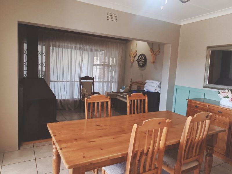 Dining room featuring tiled flooring, wainscoting, and a built-in fireplace, with an open-plan flow to the adjacent living area.