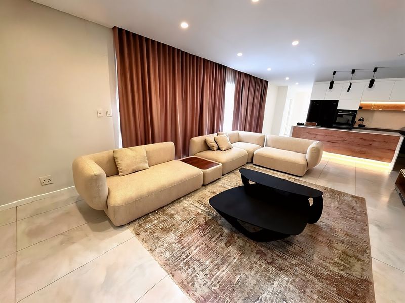 Modern open-plan living area featuring tiled floors, recessed lighting, and a contemporary kitchen with integrated appliances and a sleek island.