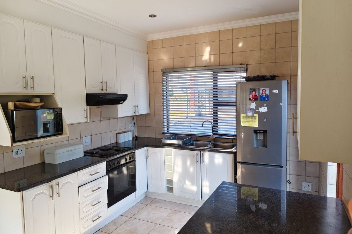 Functional kitchen featuring white cabinetry, granite countertops, tiled backsplash, and integrated appliances, offering a practical layout with ample storage and workspace.