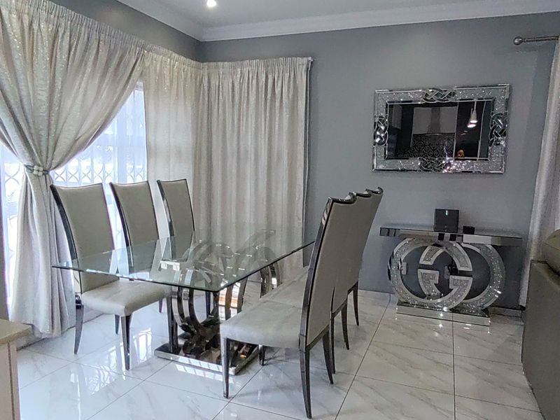 A well-maintained dining area featuring polished porcelain floor tiles, neutral grey walls, and decorative cornice detailing.