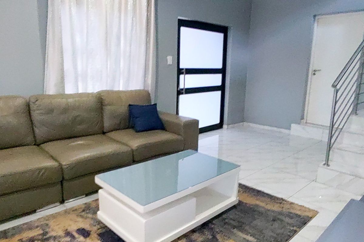 A living room featuring tiled flooring, a staircase with a metal railing, and a modern frosted glass panel door.