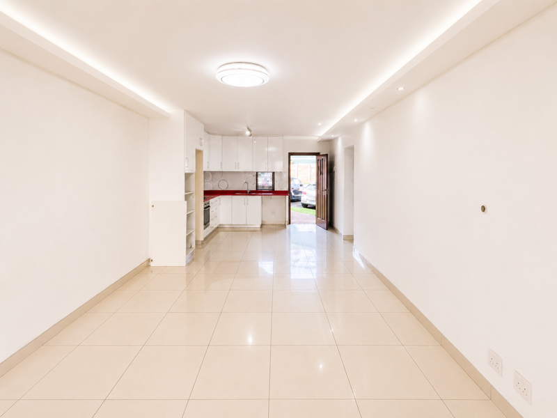 Spacious open-plan living area featuring tiled floors, recessed lighting, and a functional kitchen with built-in cabinetry and appliances.