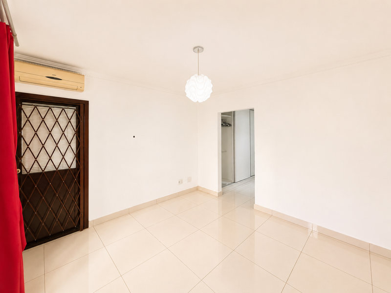 A bright, empty bedroom featuring tiled flooring, a built-in wardrobe, a security gate, and a wall-mounted air conditioning unit.
