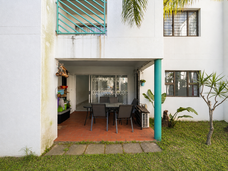 Ground floor patio area featuring terracotta tiling, a metal security gate, and access to the apartment interior, showing signs of exterior wall weathering.