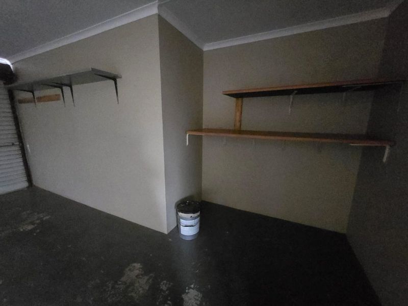 A functional garage space featuring concrete flooring and built-in wall-mounted shelving units.
