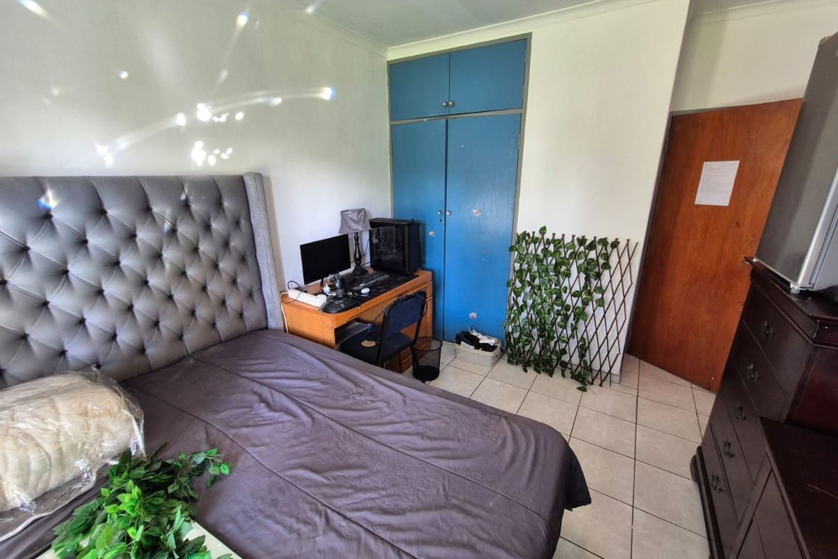 A bedroom featuring tiled flooring, coved ceilings, and built-in blue cupboards providing storage space.