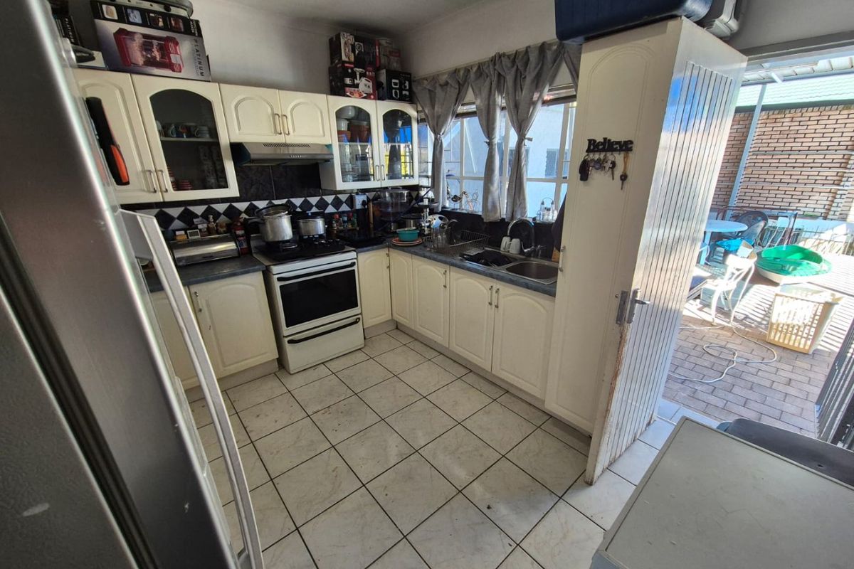 A functional kitchen featuring built-in cabinetry, a freestanding stove with extractor fan, and direct access to an outdoor patio area.