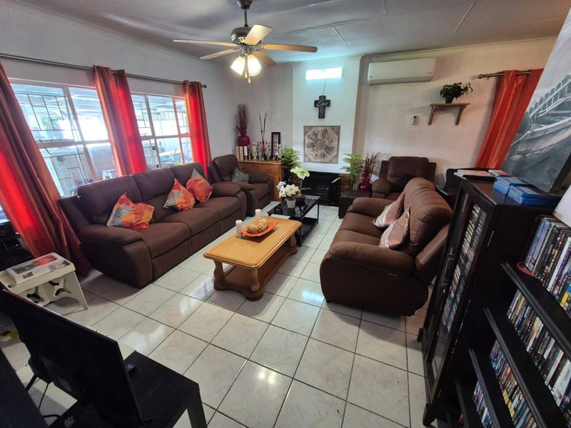 A spacious living room featuring tiled flooring, a ceiling fan, a wall-mounted air conditioner, and a fireplace.