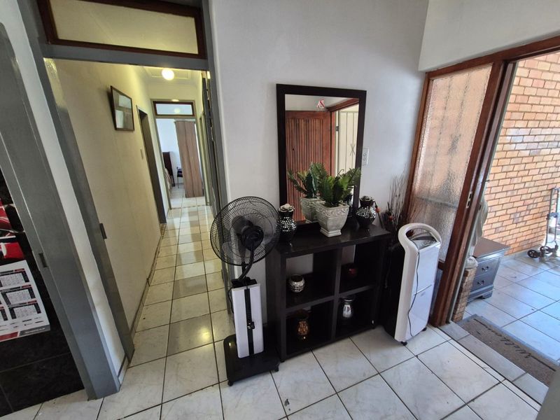 An entry area featuring tiled flooring and a glass panel door leading to an outdoor space, with a hallway providing access to other rooms.