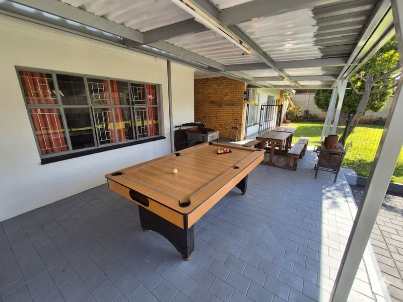 A covered outdoor patio area featuring paved flooring, a metal roof structure, and direct access to the rear garden.