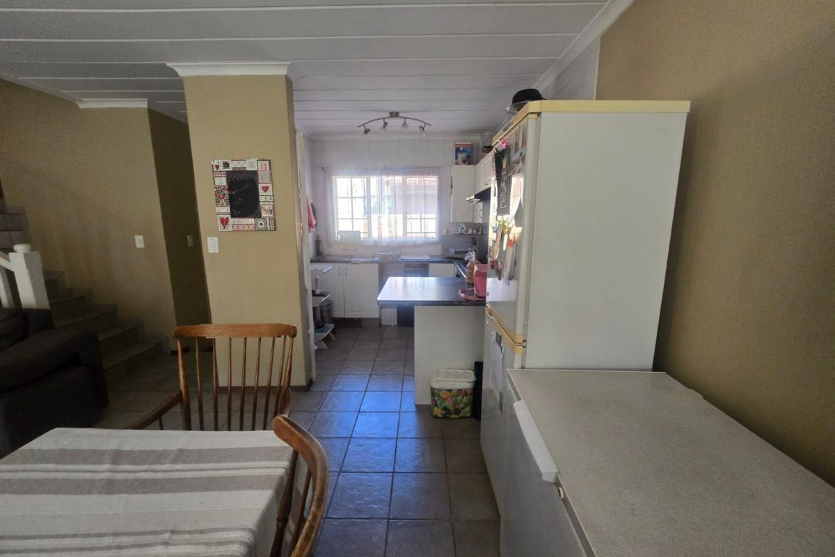 A functional kitchen area featuring tiled flooring, built-in cabinetry, and laminate countertops, offering a practical layout with potential for modern updates.