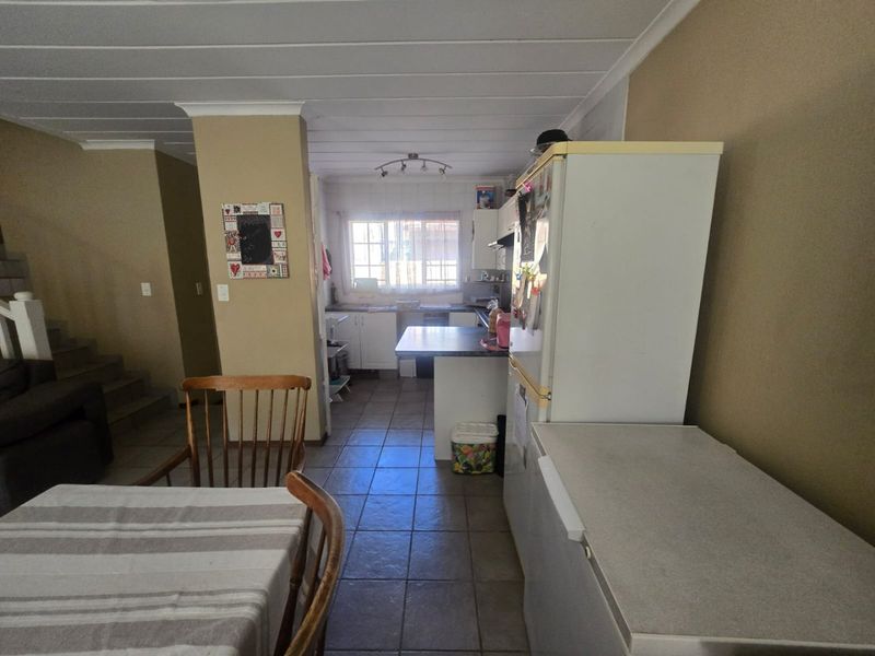 A functional kitchen area featuring tiled flooring, built-in cabinetry, and laminate countertops, offering a practical layout with potential for modern updates.