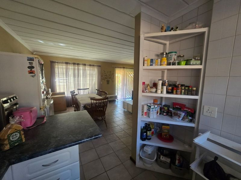 Open plan kitchen and dining area featuring tiled flooring, built-in shelving, and a functional kitchen layout with integrated oven and countertop space.