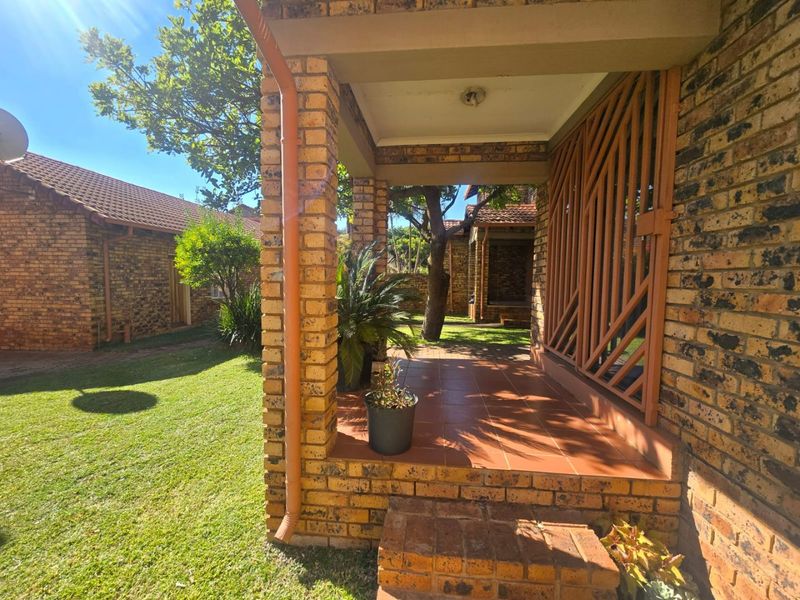 A covered brick patio area with tiled flooring, overlooking a private garden space within the townhouse complex.