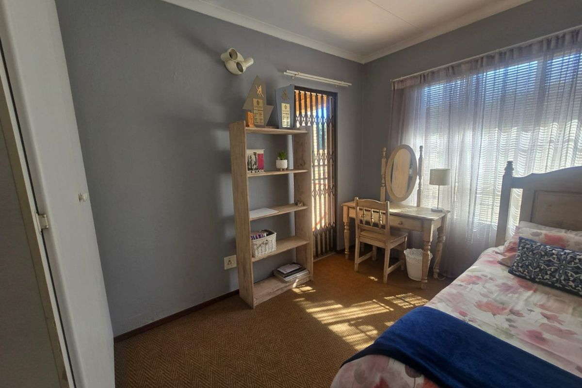 A functional bedroom featuring carpeted flooring, a security gate at the entrance, and neutral wall finishes, offering a comfortable and secure living space.