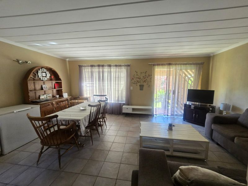 Spacious open-plan living and dining area featuring tiled flooring, a tongue and groove ceiling, and direct access to the outdoor patio through sliding glass doors.