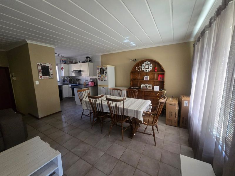 Open plan living and dining area featuring tiled floors and a connected kitchen with built-in cabinetry and appliances.