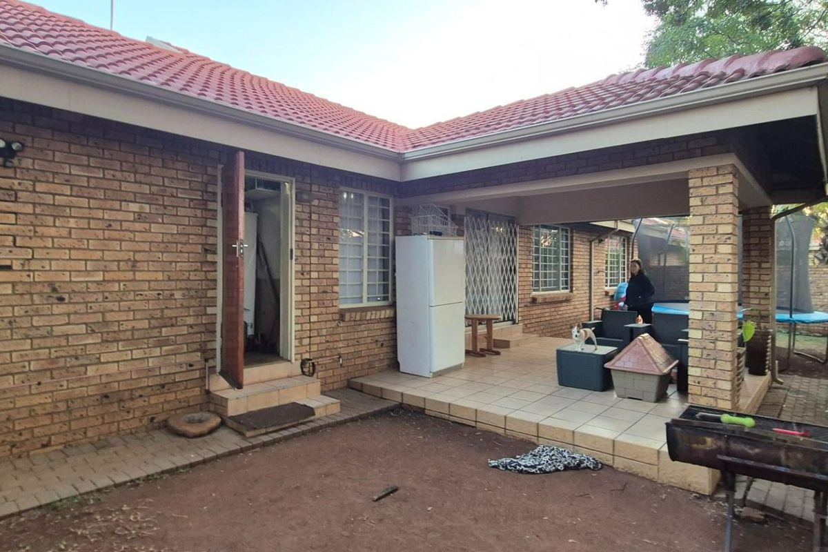 Rear view of the townhouse featuring a covered tiled patio area, brick exterior walls, and a pitched tiled roof.