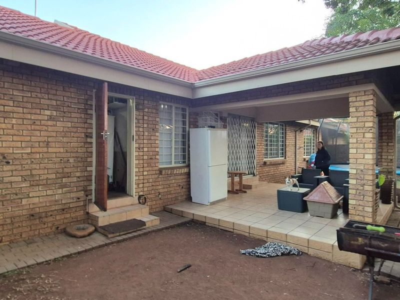 Rear view of the townhouse featuring a covered tiled patio area, brick exterior walls, and a pitched tiled roof.