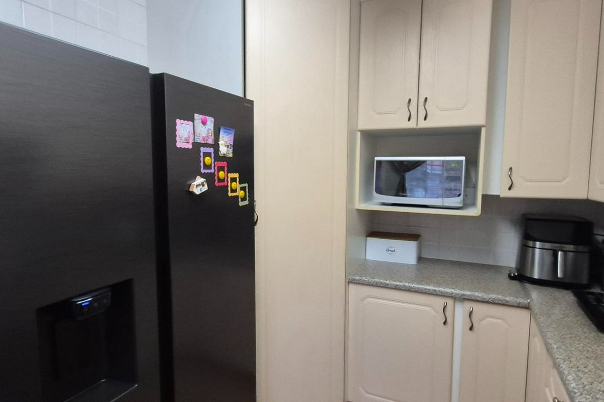 A functional kitchen featuring light-toned cabinetry, laminate countertops, and integrated appliance housing, providing a practical workspace for daily meal preparation.