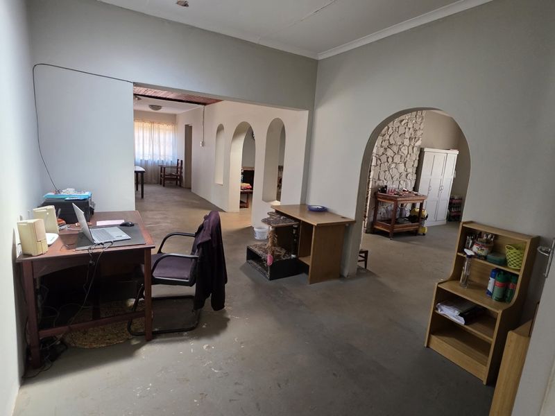 An open-plan living area featuring distinctive arched doorways and a stone feature wall, offering a versatile layout with potential for modernization.