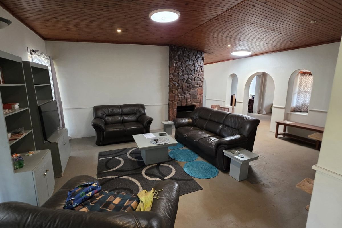 Spacious living room featuring a prominent stone fireplace, timber-clad ceiling, and distinctive archway architectural details connecting to adjacent spaces.
