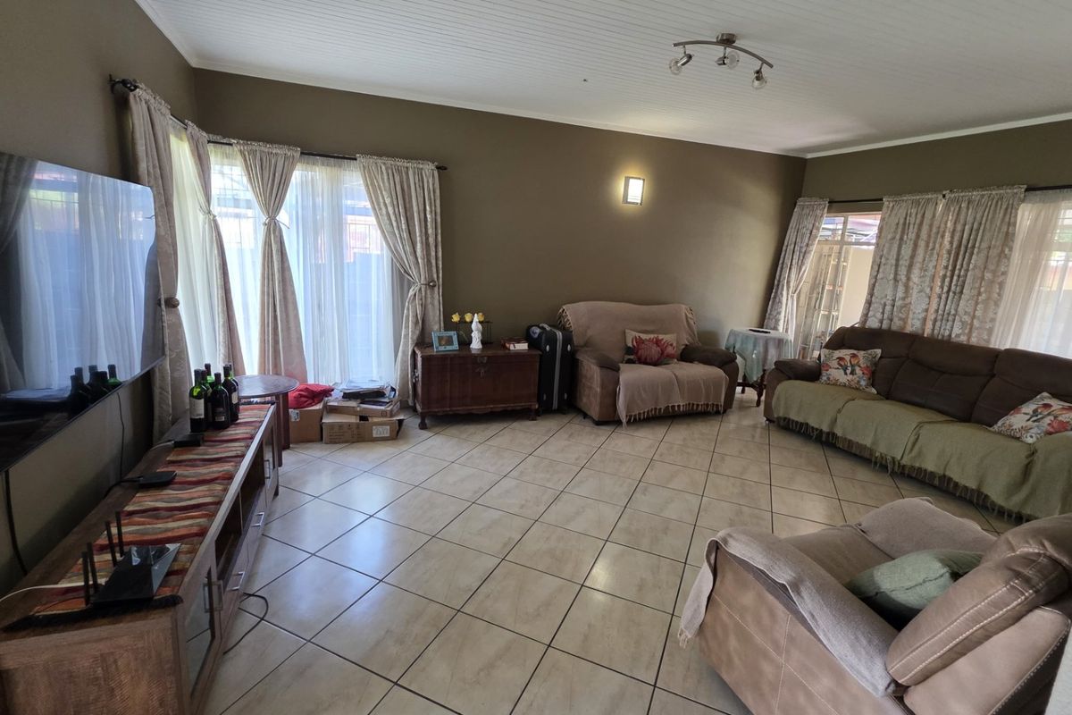 Spacious living room featuring tiled flooring, beadboard ceiling, and large sliding glass doors providing natural light.