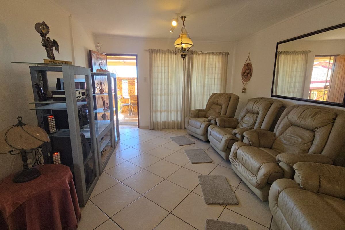 A living room featuring ceramic floor tiles, a ceiling light fixture, and a sliding glass door providing access to an outdoor patio area.