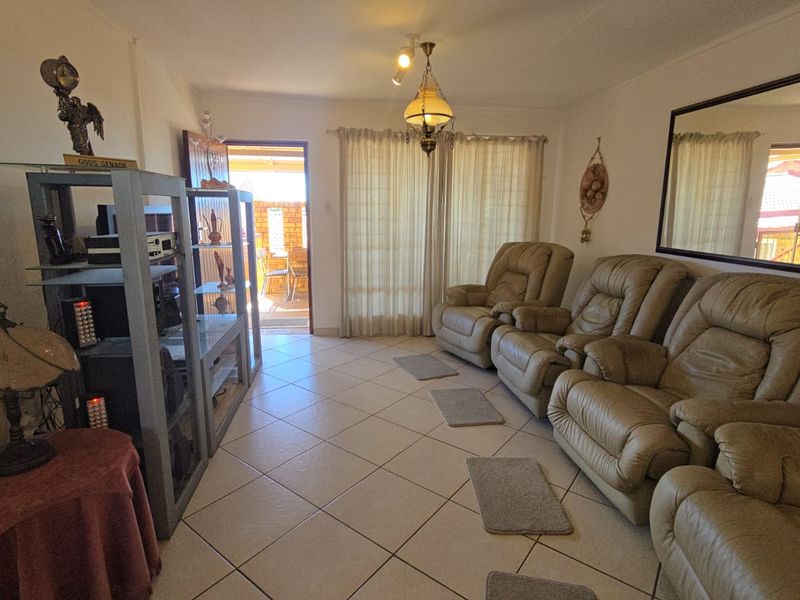 A living room featuring ceramic floor tiles, a ceiling light fixture, and a sliding glass door providing access to an outdoor patio area.
