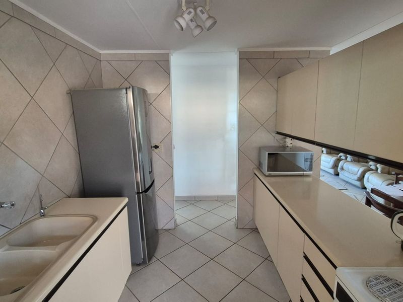 A functional kitchen featuring tiled splashbacks, ample built-in cabinetry, and a double basin sink, offering a practical layout for daily meal preparation.