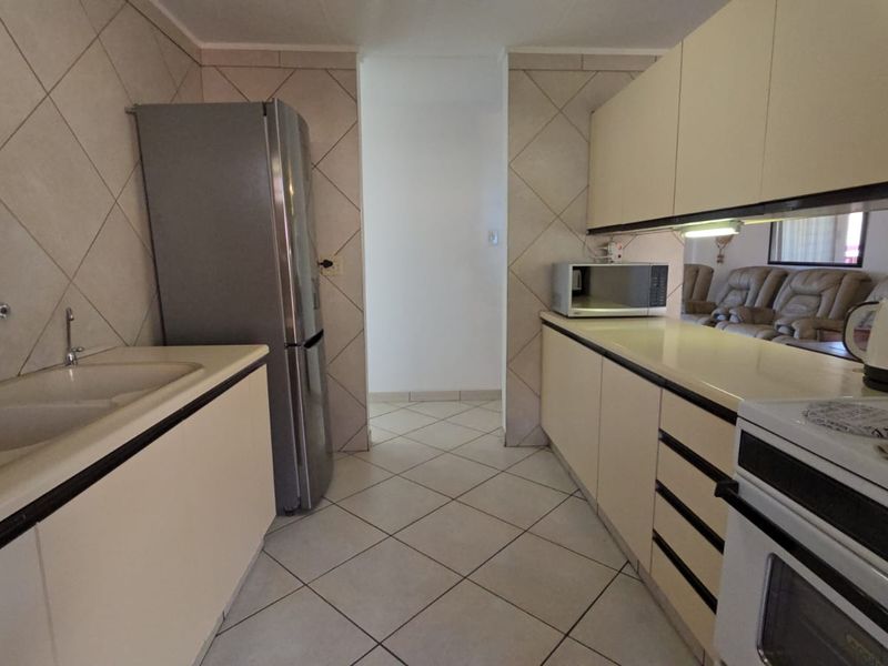 A functional kitchen featuring tiled flooring, ample built-in cabinetry, a double sink, and a built-in oven with hob.