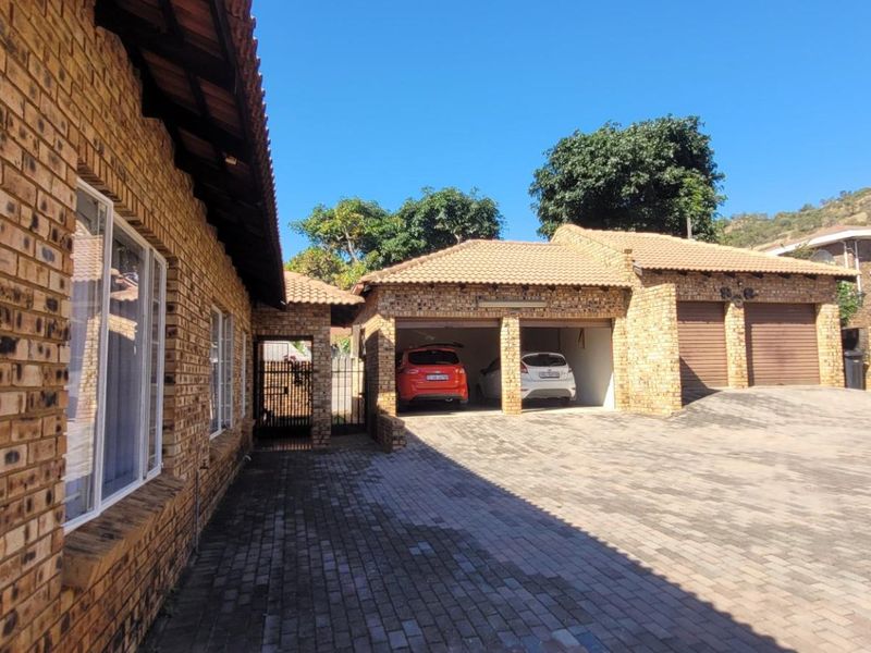 A well-maintained face brick property featuring a spacious paved driveway and a triple garage with tiled roofing.