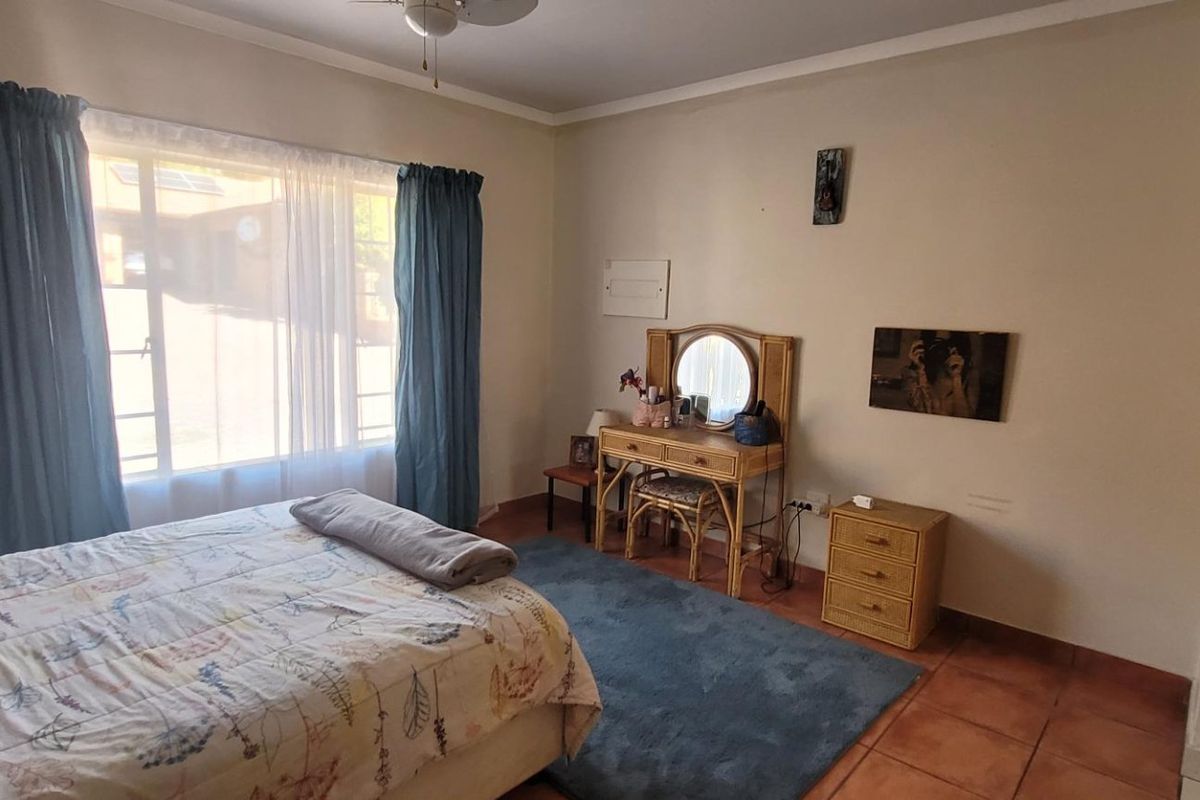 A well-lit bedroom featuring tiled flooring, a ceiling fan, and a large window providing natural light.