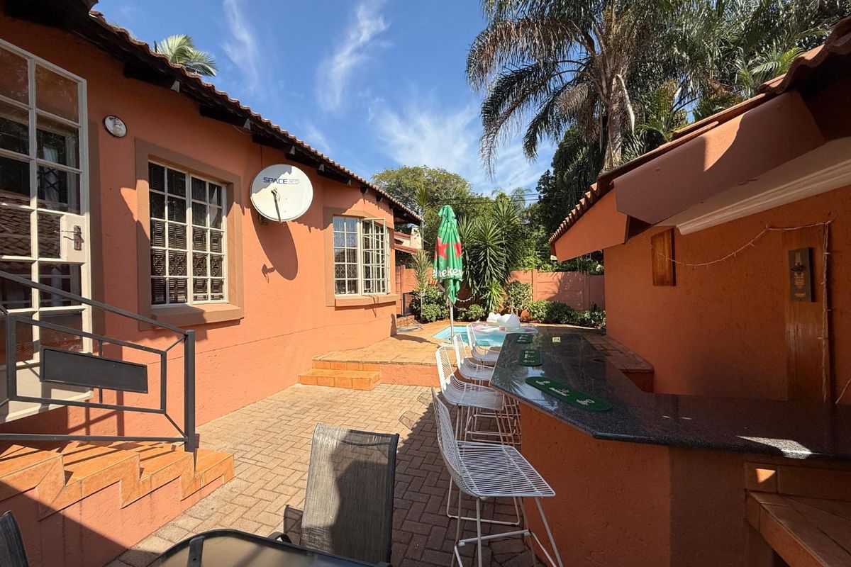 Rear courtyard featuring a paved patio, built-in bar area, and a swimming pool, providing an ideal space for outdoor entertaining.