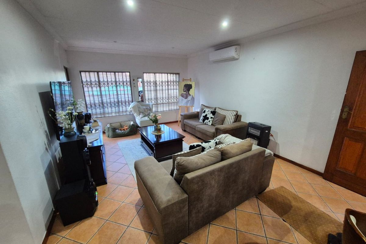 A comfortable living room featuring tiled flooring, recessed downlighting, and a wall-mounted split-system air conditioner for climate control.
