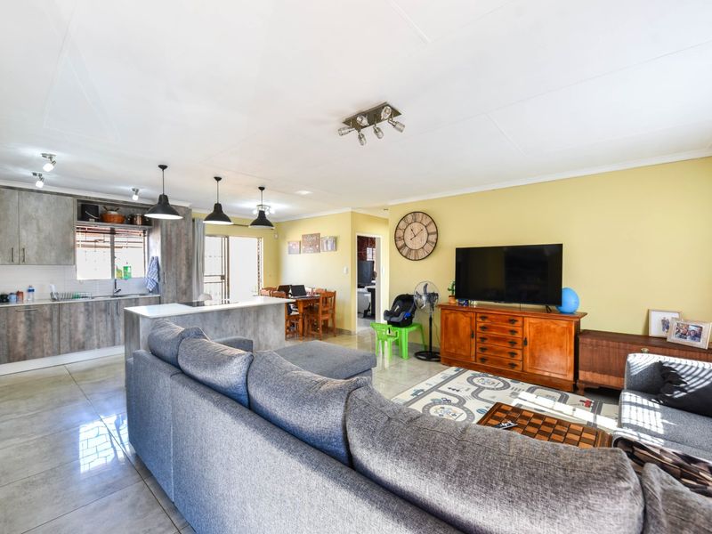 Spacious open-plan living area featuring a modern kitchen with island, tiled flooring, and seamless flow to the dining and lounge spaces.