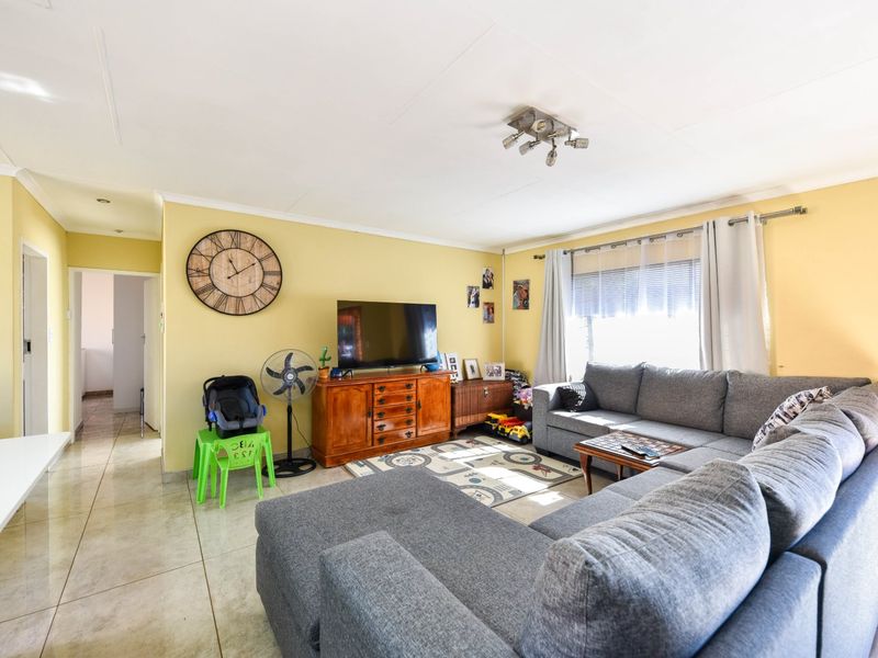 A spacious living room featuring tiled flooring and natural light, providing a comfortable and functional area for relaxation and family gatherings.