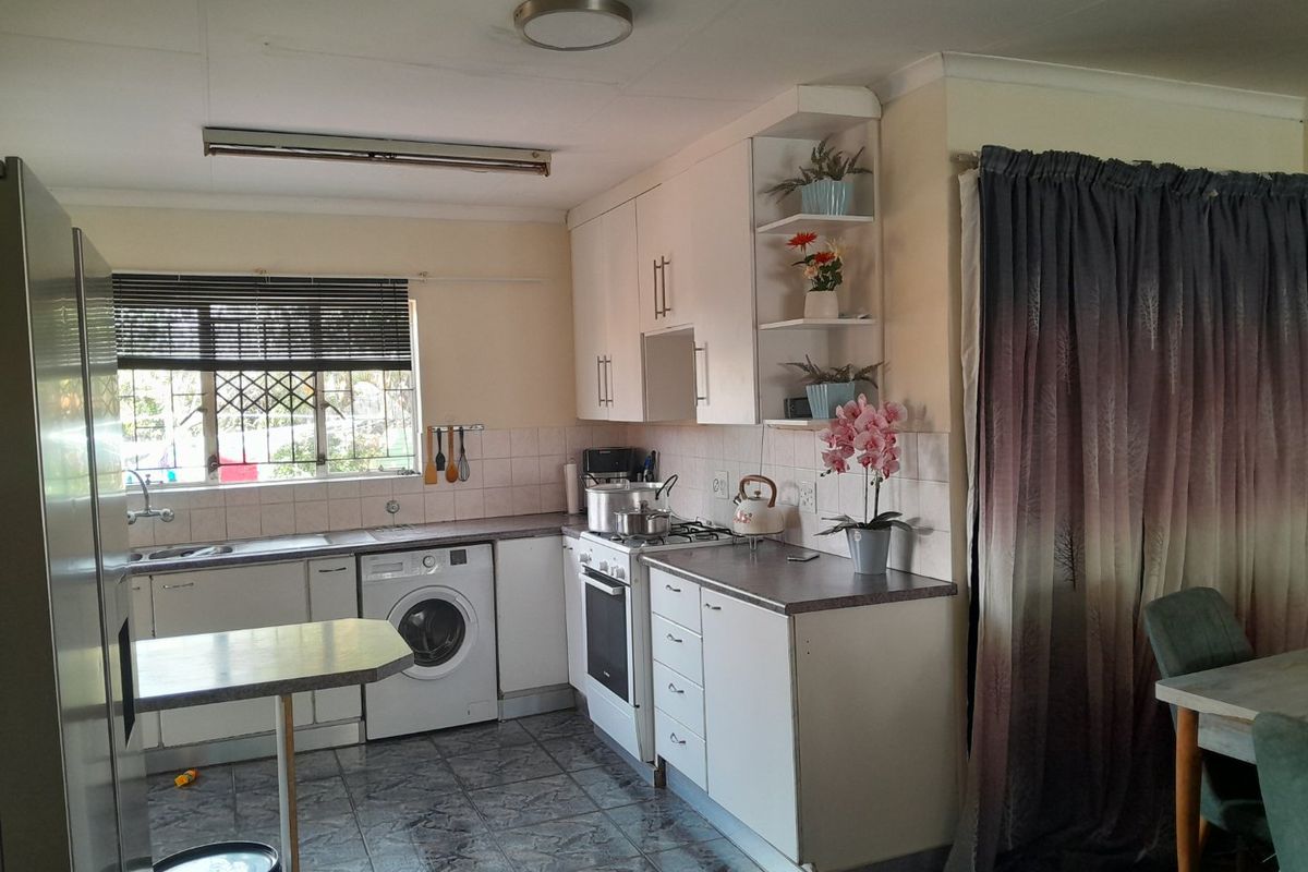 Functional kitchen featuring built-in cabinetry, laminate countertops, integrated oven and hob, tiled backsplash, and tiled flooring with security bars on the window.