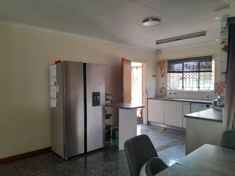 Functional kitchen featuring built-in cabinetry, tiled flooring, and a double sink, with direct access to an outdoor area.